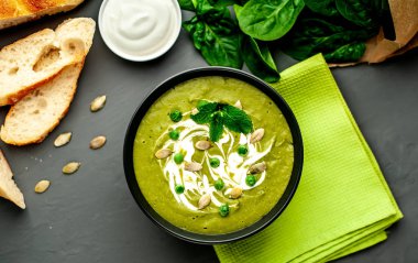 Ispanak ve brokoli yeşil krem çorbası ahşap arka planda Kabak tohumları ve Yunan yoğurt ile servis