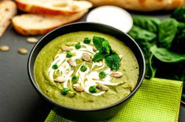 Ispanak ve brokoli yeşil krem çorbası ahşap arka planda Kabak tohumları ve Yunan yoğurt ile servis