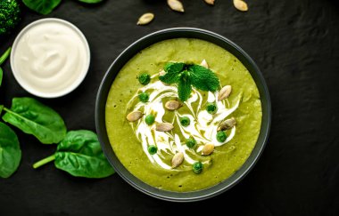 Ispanak ve brokoli yeşil krem çorbası ahşap arka planda Kabak tohumları ve Yunan yoğurt ile servis