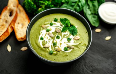 Ispanak ve brokoli yeşil krem çorbası ahşap arka planda Kabak tohumları ve Yunan yoğurt ile servis