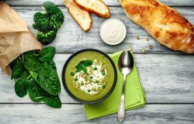 Ispanak ve brokoli yeşil krem çorbası ahşap arka planda Kabak tohumları ve Yunan yoğurt ile servis