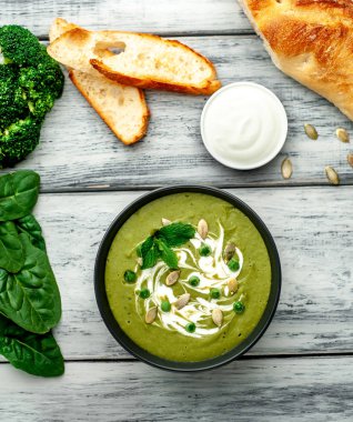 Ispanak ve brokoli yeşil krem çorbası ahşap arka planda Kabak tohumları ve Yunan yoğurt ile servis