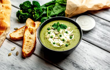 Ispanak ve brokoli yeşil krem çorbası ahşap arka planda Kabak tohumları ve Yunan yoğurt ile servis