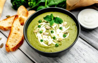 Ispanak ve brokoli yeşil krem çorbası ahşap arka planda Kabak tohumları ve Yunan yoğurt ile servis