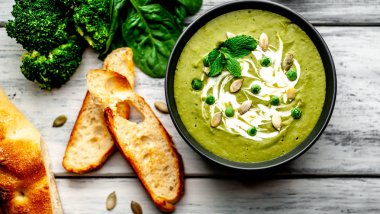 Ispanak ve brokoli yeşil krem çorbası ahşap arka planda Kabak tohumları ve Yunan yoğurt ile servis