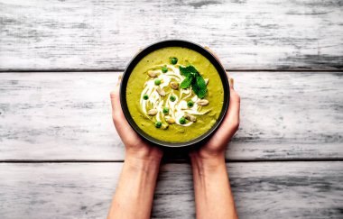 Ispanak ve brokoli yeşil krem çorbası tutan kadın elleri üst görünümü Kabak tohumları ve Yunan yoğurt ile servis