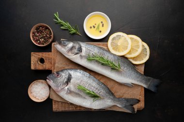 Ahşap doğrama tahtası üzerinde limon dilimleri ve biberiye dalları ile çiğ balık