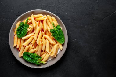 taş siyah arka plan üzerinde yeşil yaprakları ile servis domates soslu makarna