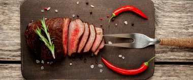 Ahşap arka planda baharat ve biberiye dalları ile taze ızgara biftek