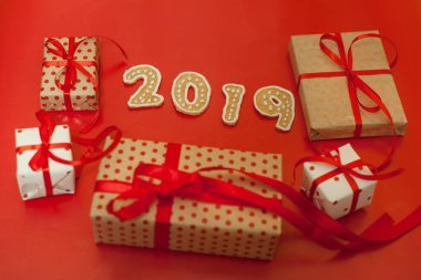 Parlak kırmızı arka plan üzerinde kırmızı yay ve 2019 çerezleri ile hediye kutuları yığını 