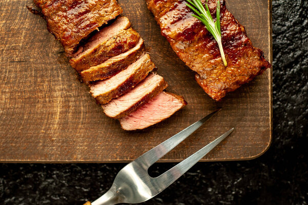 Grilled pork steaks with spices and rosemary on wooden chopping board