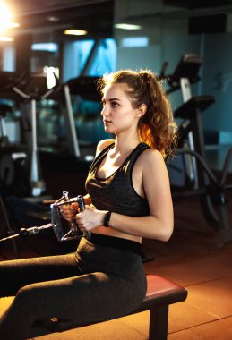 Genç sporcu kadın boş spor salonunda kas çalıştırıyor.  