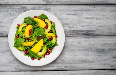 Arugula, ıspanak, dilimlenmiş mango ve avokado, nar ve ayçiçeği tohumu ile taze vegan salata