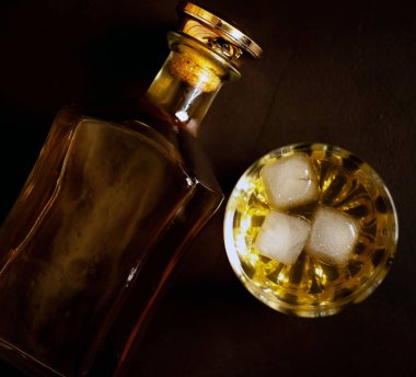 Siyah arka planda buz küpleri ve viski şişesi ile viski Bir bardak 