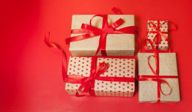 Parlak kırmızı arka plan üzerinde kırmızı yaylı hediye kutuları yığını 