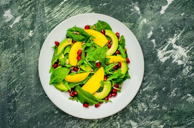 Arugula, ıspanak, dilimlenmiş mango ve avokado, nar ve ayçiçeği tohumu ile taze vegan salata