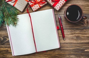 Eski ahşap arka plan üzerinde kırmızı yay ve boş defter ile hediye kutuları yığını 