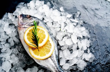 Soğuk ezilmiş buz yığını üzerinde limon dilimleri ve biberiye ile taze balık yakın görünümü