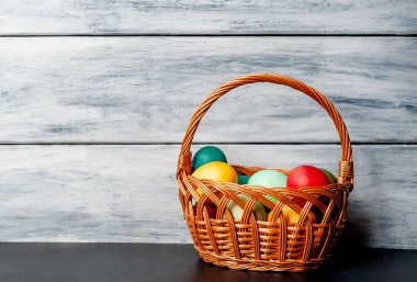 Beyaz ahşap arka plan üzerinde renkli Paskalya ile sepet yumurta
