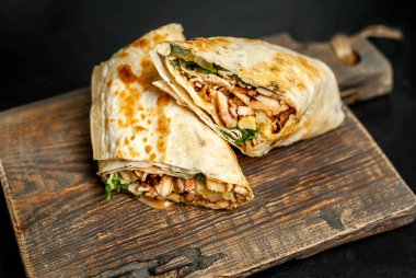 Ahşap doğrama tahtası üzerinde tavuk ve sebze ile sarılmış ev yapımı Meksika burrito 