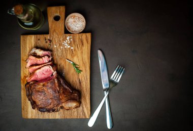 Siyah taş arka plan üzerinde ahşap doğrama tahtası üzerinde baharat ile Yağlı ızgara domuz biftek