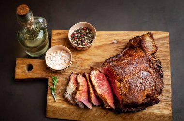 Siyah taş arka plan üzerinde ahşap doğrama tahtası üzerinde baharat ile Yağlı ızgara domuz biftek