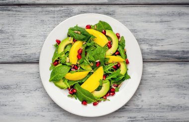 Arugula, ıspanak, dilimlenmiş mango ve avokado, nar ve ayçiçeği tohumu ile taze vegan salata