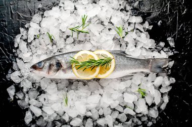 Soğuk ezilmiş buz yığını üzerinde limon dilimleri ve biberiye ile taze balık yakın görünümü