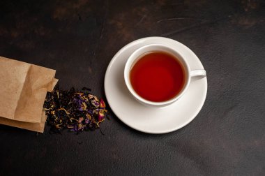 siyah arka plan üzerinde çiçek demlemek dolu kağıt torba ile taze çay fincan
