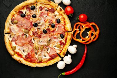Siyah taş arka plan üzerinde mantar, domates, zeytin ve jambon ile taze ev yapımı pizza
