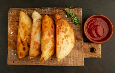 Ahşap doğrama tahtası üzerinde domates soslu Geleneksel Latin Amerika kızarmış empanadas 