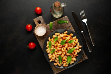 taş siyah arka plan üzerinde ahşap doğrama tahtası üzerinde domates soslu makarna