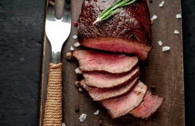 Siyah taş arka plan üzerinde baharat ve biberiye dal ile Taze ızgara biftek