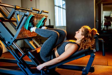 Genç sporcu kadın boş spor salonunda kas çalıştırıyor.  