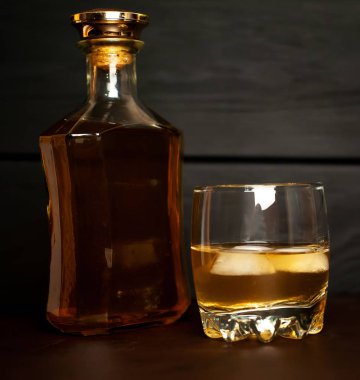 Siyah arka planda buz küpleri ve viski şişesi ile viski Bir bardak 