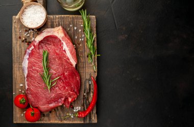 Ahşap doğrama tahtasında biberiye, domates ve biberiye ile taze çiğ biftek 