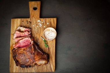 Siyah taş arka plan üzerinde ahşap doğrama tahtası üzerinde baharat ile Yağlı ızgara domuz biftek