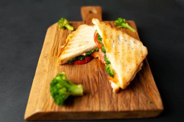 Ahşap doğrama tahtasında jambon, taze brokoli ve peynirile taze ızgara sandviçler