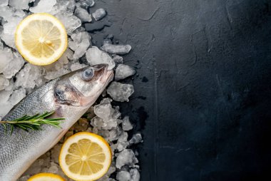 Soğuk ezilmiş buz yığını üzerinde limon dilimleri ve biberiye ile taze balık yakın görünümü