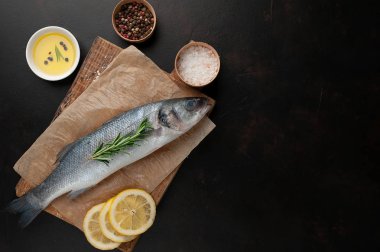 Ahşap doğrama tahtası üzerinde limon dilimleri ve biberiye dal ile çiğ balık