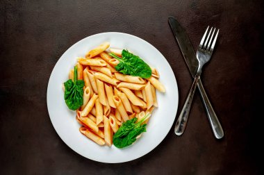 taş siyah arka plan üzerinde yeşil yaprakları ile servis domates soslu makarna