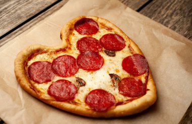 ahşap arka plan üzerinde salam ile peynir kalp pizza