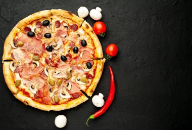 Siyah taş arka plan üzerinde mantar, domates, zeytin ve jambon ile taze ev yapımı pizza