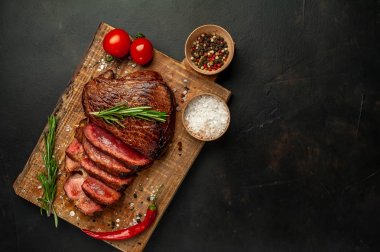 Taze sığır eti biftek ahşap tahta üzerinde domates, biberiye biberiye ve biberiye dalları ile servis