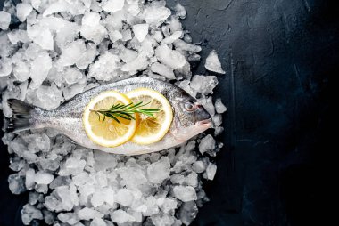 Soğuk ezilmiş buz yığını üzerinde limon dilimleri ve biberiye ile taze balık yakın görünümü