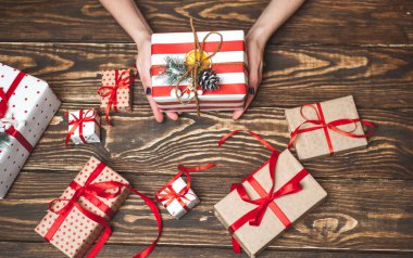 Eski ahşap arka plan üzerinde kırmızı yay ile kadın elleri dekorasyon hediye kutuları 