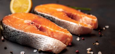 Siyah taş arka plan üzerinde baharat ve limon ile taze çiğ somon biftek