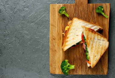 Ahşap doğrama tahtasında jambon, taze brokoli ve peynirile taze ızgara sandviçler