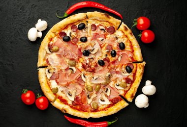 Siyah taş arka plan üzerinde mantar, domates, zeytin ve jambon ile taze ev yapımı pizza