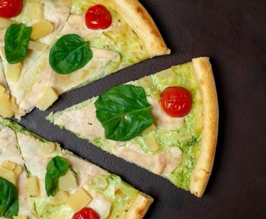 siyah taş arka plan üzerinde kiraz domates ve taze ıspanak yaprakları ile pizza